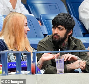 Zayn 在比赛开始时与朋友聊天,脱掉夹克露出深绿色衬衫