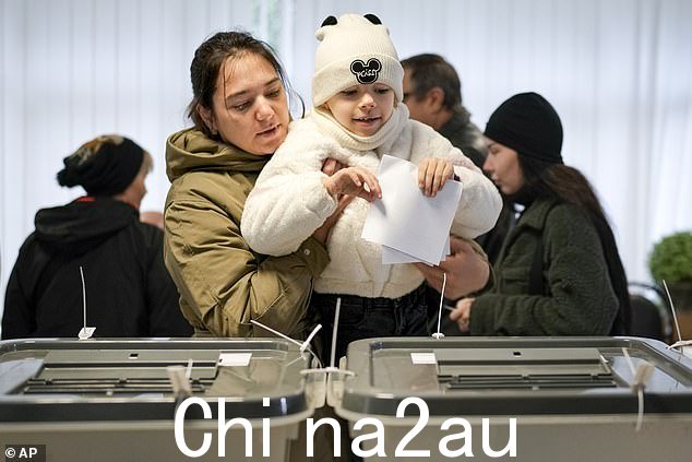 摩尔多瓦基希讷乌总统选举和全民公投期间,一名母亲抱着一个孩子投票
