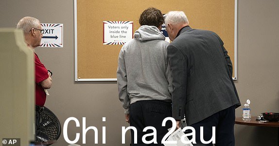 民主党副总统候选人明尼苏达州州长蒂姆·沃尔兹(右)和他的儿子格斯·沃尔兹首次投票的选民于 2024 年 10 月 23 日星期三在明尼苏达州圣保罗拉姆齐县选举办公室提前投票。(Renée Jones Schneider/Star Tribune via AP, Pool )