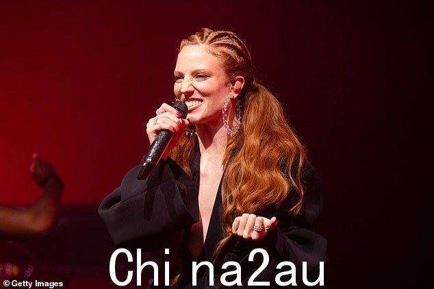 握住我的手女歌手穿着大胆的舞台服装展示了她的深V领口,并配有一套喇叭袖