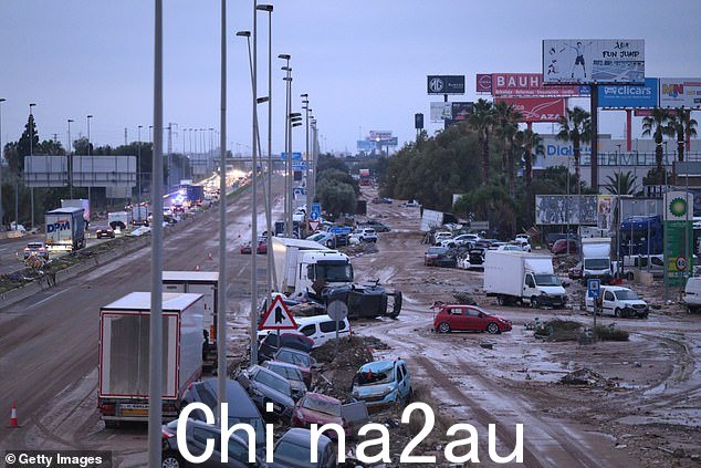 2024 年 11 月 1 日,巴伦西亚郊区马萨纳萨市附近的 V-31 高速公路上,人们乘坐汽车和卡车行走,这些汽车和卡车是近期洪水冲走的废墟
