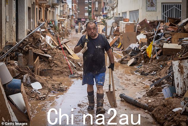 2024 年 11 月 4 日,西班牙派波塔,大雨和洪水袭击该国大部分地区后,一名男子正在清理房屋