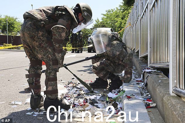 韩国2024 年 6 月 2 日,韩国仁川,身穿防护装备的士兵检查可能由朝鲜发射的气球中的垃圾